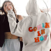 two girls laughing and dancing and one girl in a tan coming in hot hangover hoodie